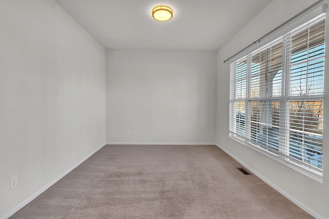 empty room featuring carpet floors, baseboards, and visible vents