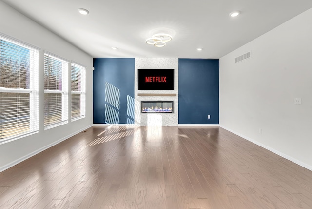 unfurnished living room featuring recessed lighting, a fireplace, wood finished floors, visible vents, and baseboards