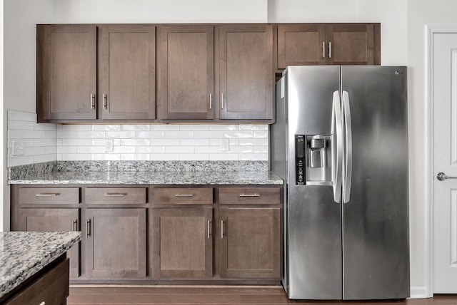 kitchen featuring light stone counters, backsplash, and stainless steel fridge