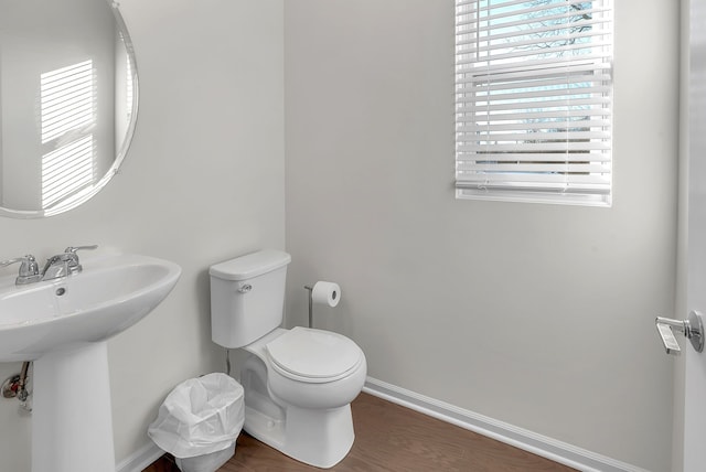 bathroom with toilet, a sink, baseboards, and a wealth of natural light