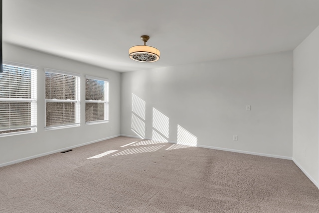 unfurnished room with light carpet, visible vents, and baseboards