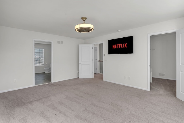 unfurnished bedroom featuring a spacious closet, carpet flooring, visible vents, and baseboards