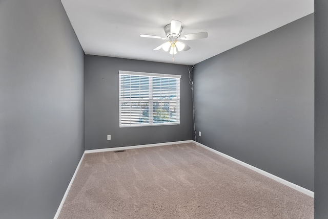 carpeted empty room with a ceiling fan, visible vents, and baseboards