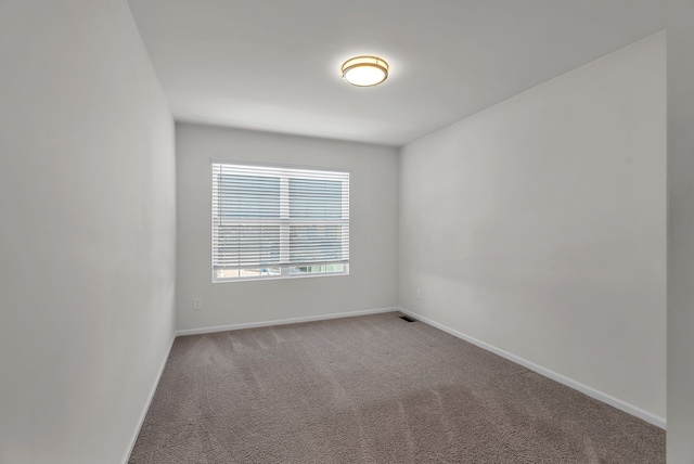 carpeted empty room featuring baseboards