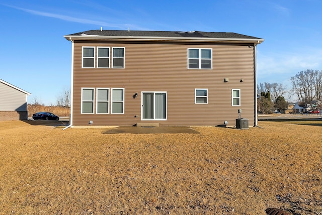 rear view of house with central AC and a yard