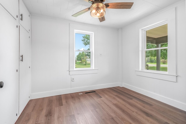 empty room with ceiling fan, a healthy amount of sunlight, and hardwood / wood-style floors