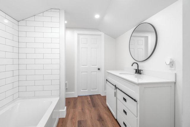 bathroom with vanity, hardwood / wood-style flooring, vaulted ceiling, and tiled shower / bath combo