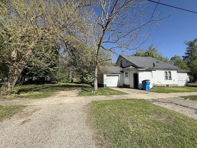 view of front facade featuring driveway, a front lawn, a garage, and roof with shingles