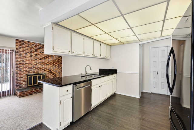 kitchen with sink, white cabinetry, dishwasher, black refrigerator, and a fireplace