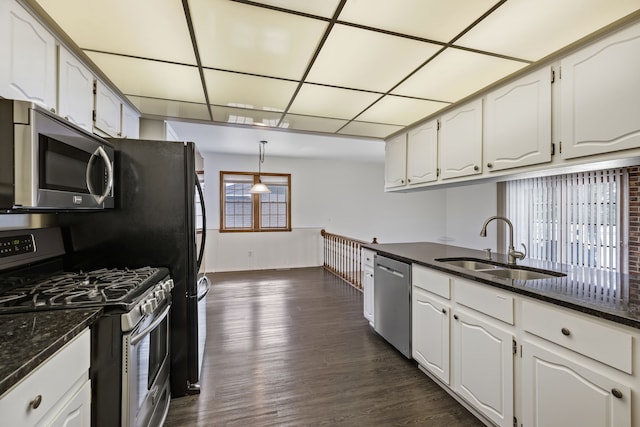 kitchen featuring sink, white cabinetry, dark stone counters, stainless steel appliances, and dark hardwood / wood-style flooring