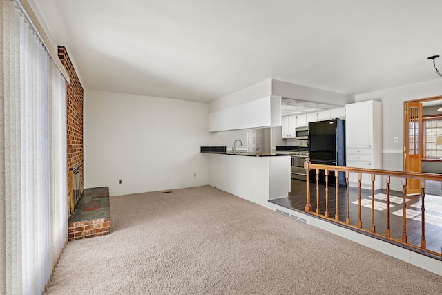 carpeted living room featuring sink and a brick fireplace