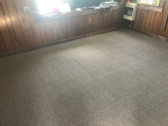 spare room featuring wooden walls, carpet flooring, and heating unit