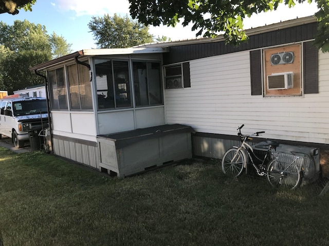 view of side of home featuring a lawn, cooling unit, and a sunroom