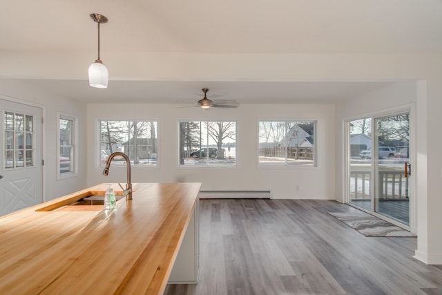 unfurnished dining area featuring light wood-type flooring, sink, and a baseboard heating unit