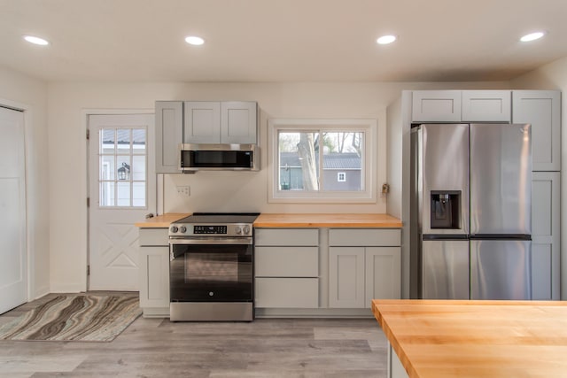 kitchen with butcher block countertops, light hardwood / wood-style flooring, and appliances with stainless steel finishes