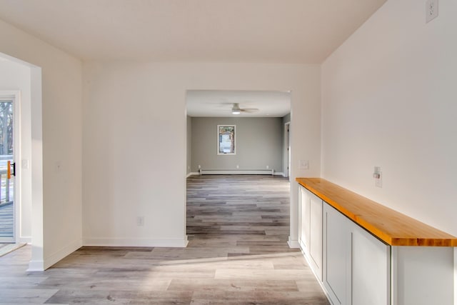 spare room with baseboard heating, ceiling fan, and light wood-type flooring