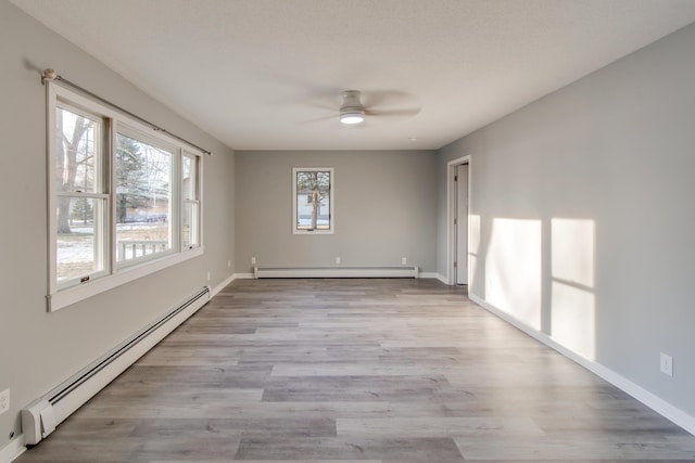 spare room with baseboard heating, ceiling fan, and light hardwood / wood-style floors