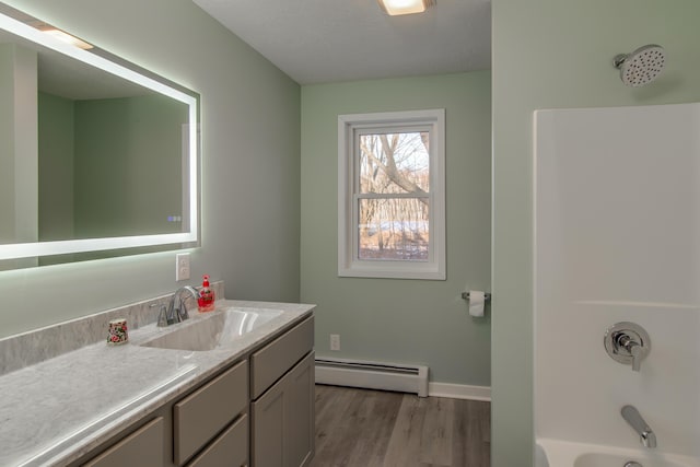 bathroom with a baseboard radiator, washtub / shower combination, hardwood / wood-style flooring, vanity, and a textured ceiling