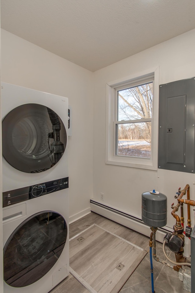 clothes washing area featuring stacked washer / dryer, electric panel, and wood-type flooring