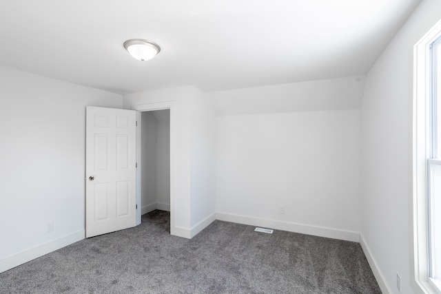 unfurnished bedroom featuring lofted ceiling and carpet flooring