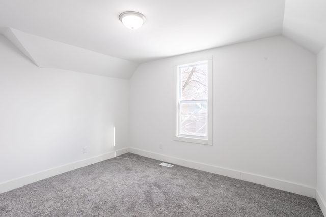 additional living space featuring vaulted ceiling and carpet