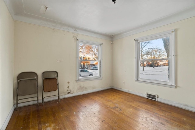 spare room with visible vents, baseboards, and wood finished floors