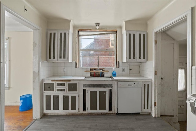 kitchen featuring dark wood-style flooring, tasteful backsplash, white cabinets, white dishwasher, and a sink