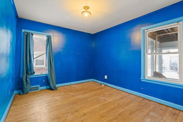 empty room featuring light wood finished floors, baseboards, and visible vents