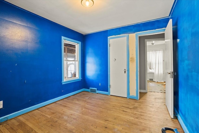 unfurnished bedroom with light wood-type flooring, visible vents, and multiple windows