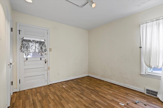 unfurnished room featuring wood finished floors, visible vents, and baseboards