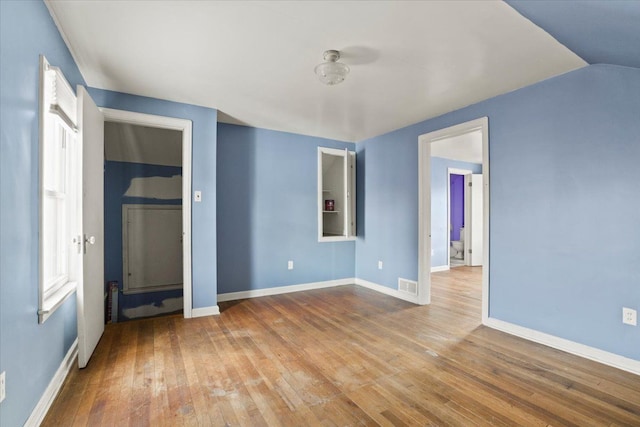 unfurnished room with baseboards, visible vents, and wood finished floors