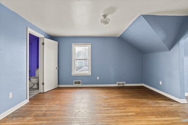 bonus room featuring vaulted ceiling, light wood-style flooring, visible vents, and baseboards