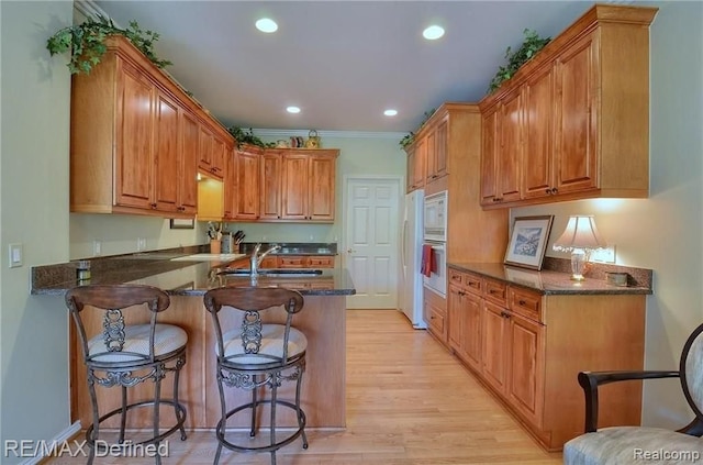 kitchen featuring sink, dark stone countertops, white appliances, and kitchen peninsula