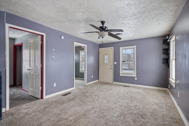 carpeted spare room with visible vents, ceiling fan, a textured ceiling, and baseboards