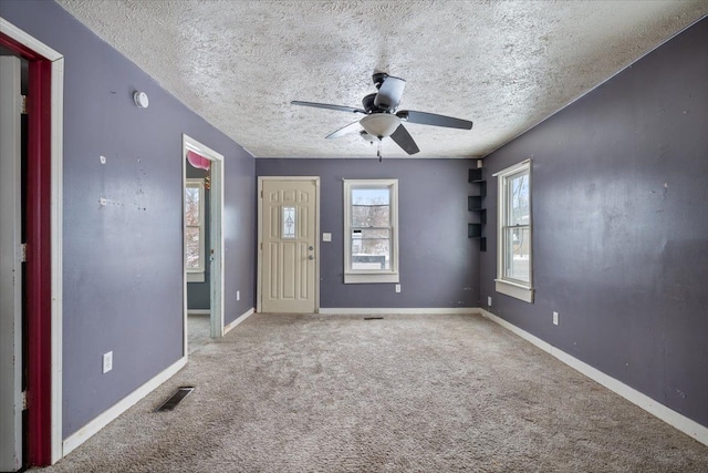 foyer entrance featuring carpet floors, visible vents, baseboards, and a textured ceiling