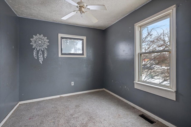 unfurnished room featuring a textured ceiling, ceiling fan, carpet floors, visible vents, and baseboards