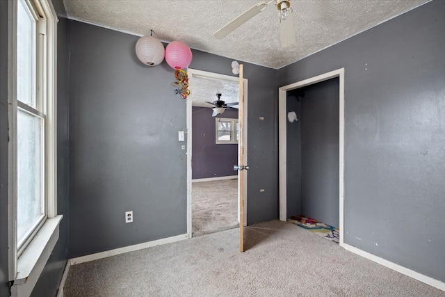 carpeted spare room featuring ceiling fan, a textured ceiling, and baseboards