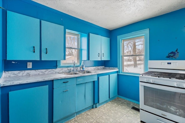 kitchen featuring white gas stove, light countertops, visible vents, a sink, and blue cabinets