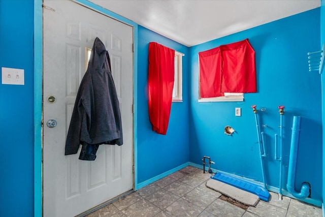 laundry area featuring laundry area, stone finish flooring, and baseboards