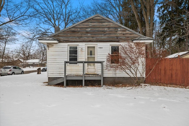 bungalow-style home with a chimney and fence