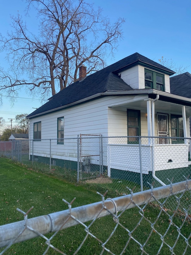 view of property exterior with a fenced front yard, roof with shingles, a yard, a chimney, and a porch