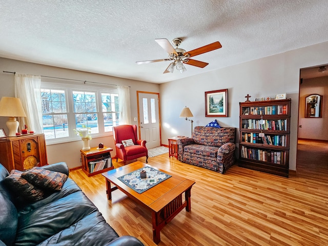 living room featuring ceiling fan, a textured ceiling, and light wood-type flooring