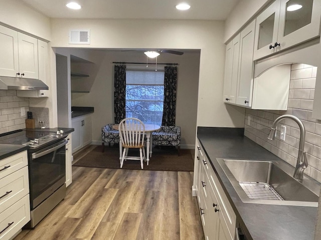 kitchen featuring dark countertops, a sink, white cabinets, and stainless steel electric stove