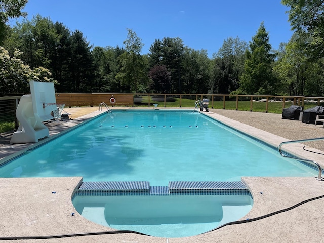 view of swimming pool featuring a pool with connected hot tub, fence, and a patio