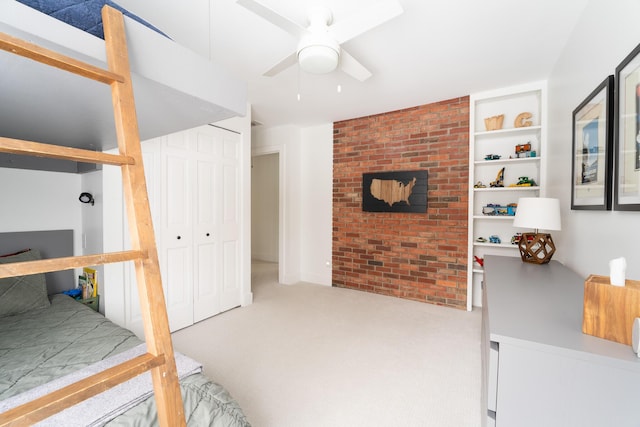 bedroom with carpet floors, brick wall, a ceiling fan, and a closet