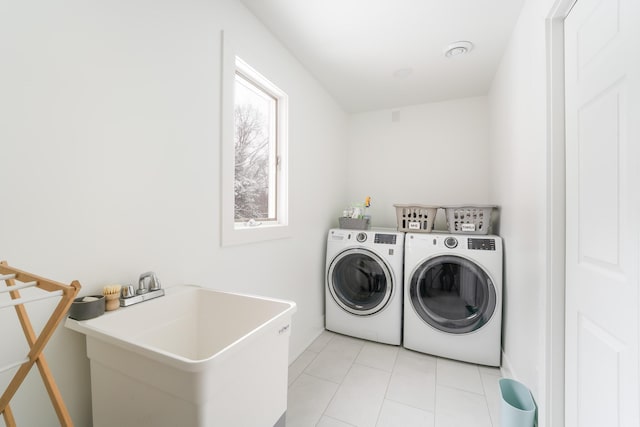 laundry area with laundry area, separate washer and dryer, a sink, and light tile patterned flooring