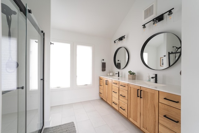 bathroom with double vanity, lofted ceiling, visible vents, a sink, and baseboards