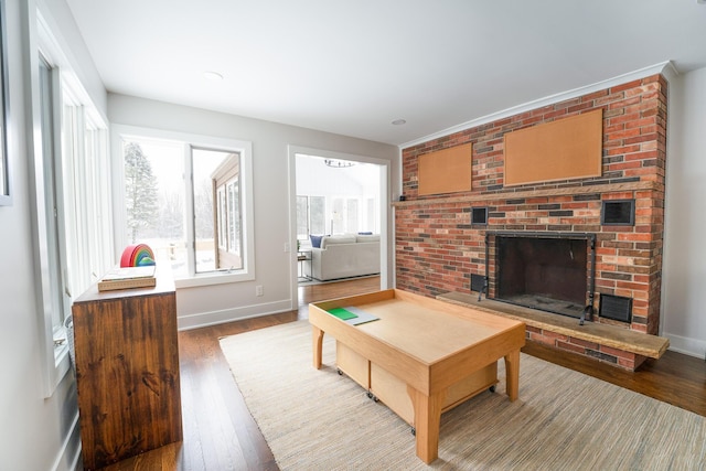 living room featuring a brick fireplace, wood finished floors, and baseboards