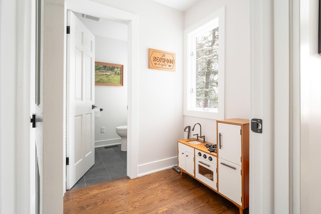 hallway featuring dark wood-type flooring, visible vents, and baseboards