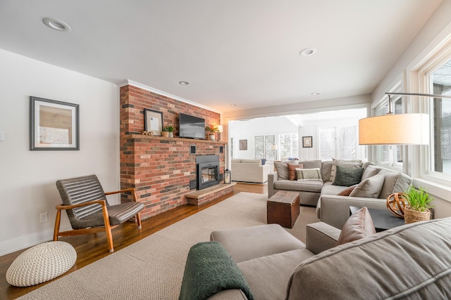 living area featuring recessed lighting, a fireplace, baseboards, and wood finished floors